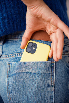 Anonymous woman putting smartphone into back pocket of jeans