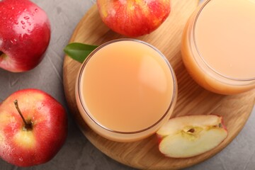 Tasty apple juice in glasses and fresh fruits on grey table, flat lay