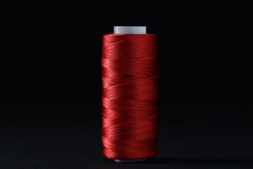 Spool of red sewing thread on black background