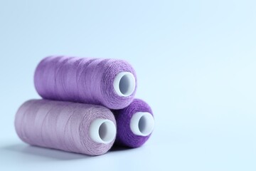 Spools of colorful sewing threads on light background, closeup. Space for text