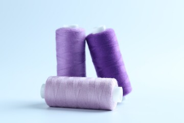 Spools of colorful sewing threads on light background, closeup