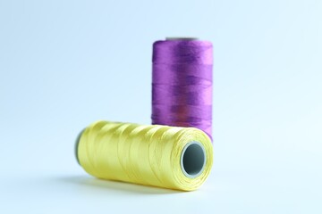 Spools of colorful sewing threads on light background, closeup