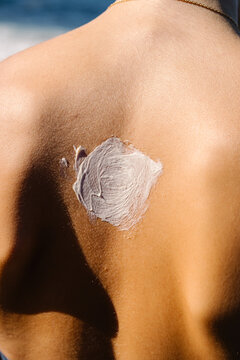 Back of unknown young woman, showing sunscreen lotion evenly applied