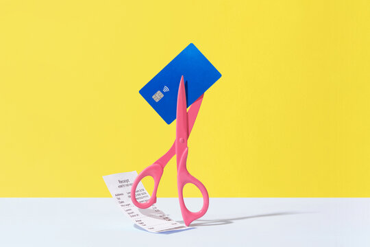 Scissors Cutting Credit Card And Cash Receipt on Yellow Background