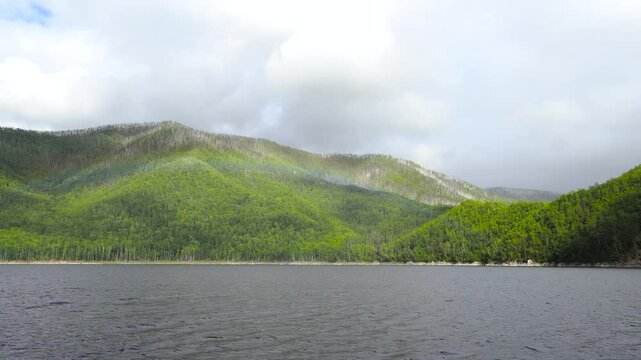 View from a boat. The boat moves along the lake past green hills. Zeya Reservoir.