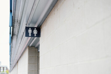 Public restroom sign with man and woman symbol on white brick wall