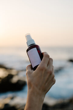 Anonymous hand holding a spray bottle of a beauty product