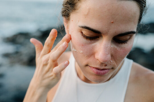 Lady applies sunscreen on her face to protect her from imperfections