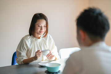 A Japanese couple, a woman in her 30s and a man in his 20s, are enjoying afternoon tea time at home.