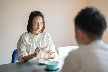 A Japanese couple, a woman in her 30s and a man in his 20s, are enjoying afternoon tea time at home.