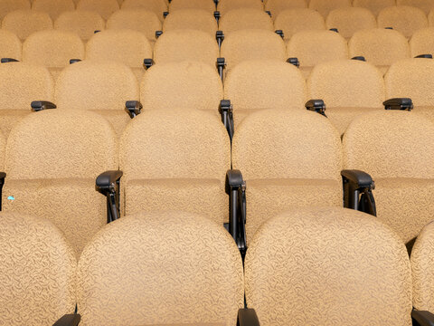 View of brightly lit yellow lecture seats, one with gum