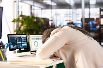 Tired businesswoman at work sleeping on desk while working on laptop to solve business tasks,...