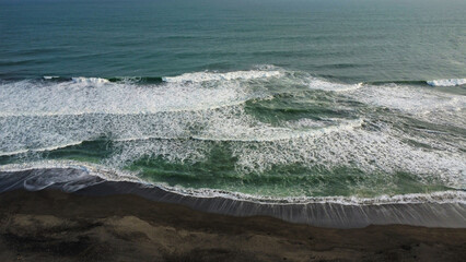 A beach with black sand seen from above