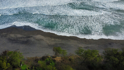 A beach with black sand seen from above