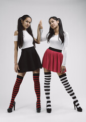 Twin sisters wearing colorful knee high socks and skirts giving