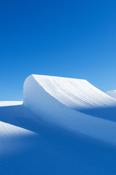 Sunset lights on big air jumps in snow park.