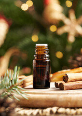 A dark bottle of aromatherapy essential oil with Ceylon cinnamon sticks and Christmas decoration