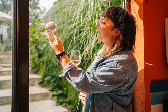 Woman Admiring a Disco Ball with a Glass of Wine