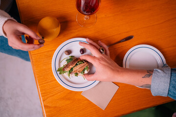 Hand Picking Food from a Plate with Drinks on Wooden Table