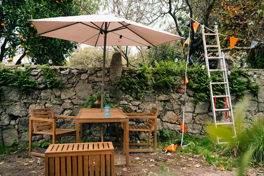 Outdoor Wooden Table and Chairs with Umbrella in Garden Setting

