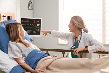 Doctor explaining vital signs to patient lying in hospital bed