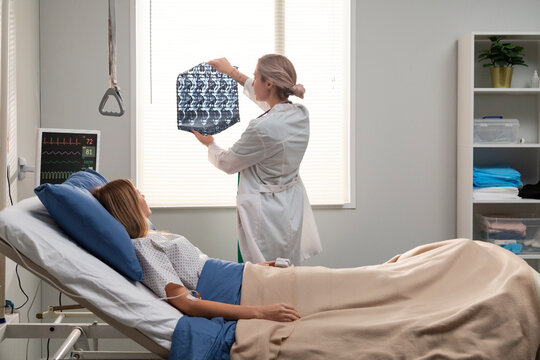 Doctor examining medical scan of patient in hospital bed