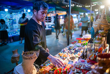 Traditional Thai Artisan Arranging Sacred Items at a Night Market