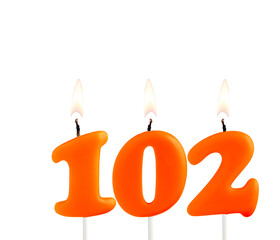 Lit birthday candle - Candle number 102 on white background.