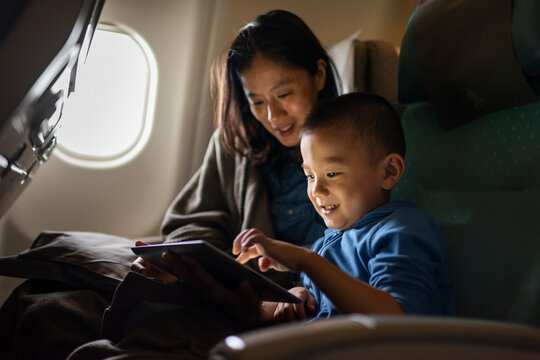 Boy and Mother Sharing a Tablet on an Airplane Flight