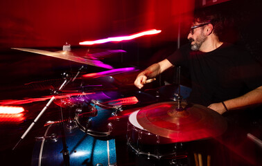 Energetic Drummer Performing Live on Stage with Vivid Lighting