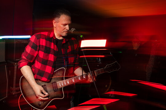 Rock musician performs under vibrant stage lights at concert