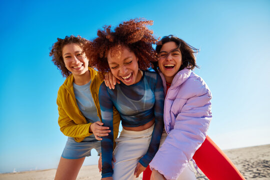 Happy diverse friends hugging on beach