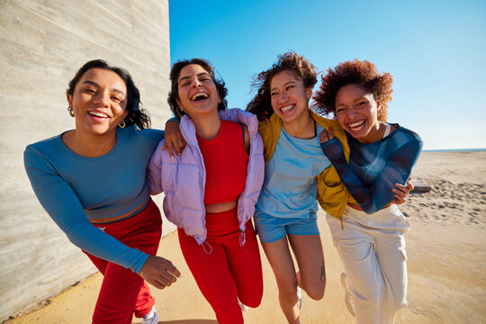 Cheerful diverse friends hugging on beach