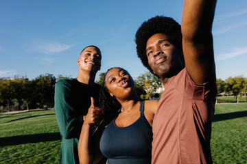 Three active friends in sports attire take a cheerful selfie outdoors