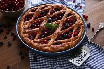 Delicious currant pie with fresh berries on wooden table
