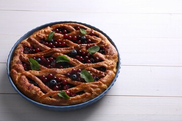 Delicious currant pie and fresh berries on white wooden table, space for text