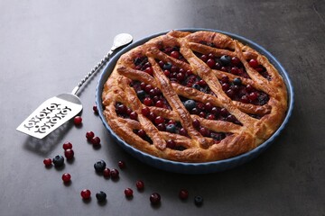 Delicious currant pie with fresh berries and spatula on grey table