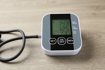 Blood pressure measuring device on wooden table, closeup