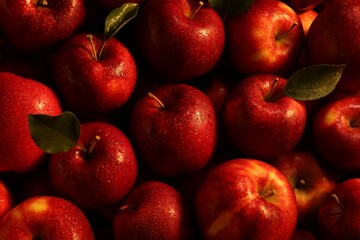 Fresh ripe red apples and green leaves as background, closeup