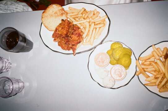 Fried chicken sandwich, fries, pickles, and sauces captured on 35mm.