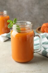 Fresh carrot juice and mint in mason jar on gray textured table