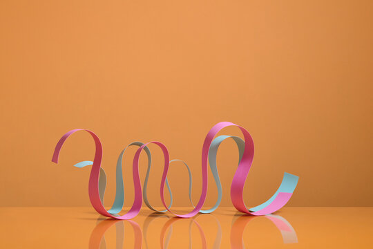 Colorful Curled Ribbons Against a Minimalist Orange Background