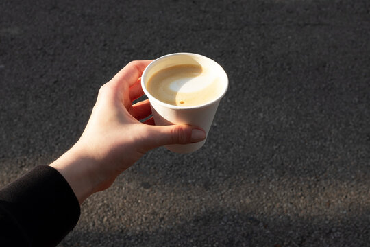Pov/point of view of person holding take away cappuccino coffee cup