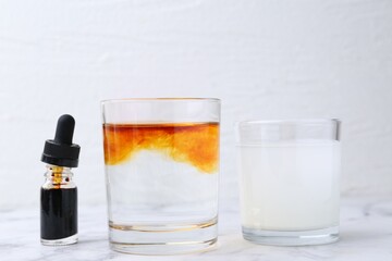 Iodine starch test. Bottle of aqueous iodine, glasses with water-dissolved iodine and starch solution on white marble table, closeup