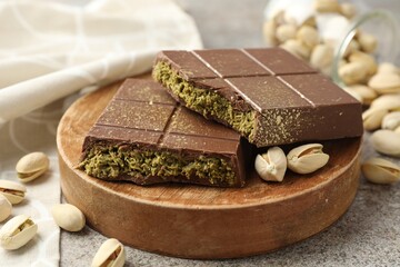 Pieces of Dubai chocolate bar with pistachios and knafeh on grey table, closeup