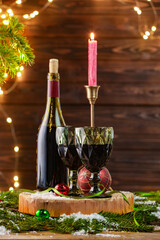 Red wine and beautiful Christmas decor on wooden table against blurred festive lights