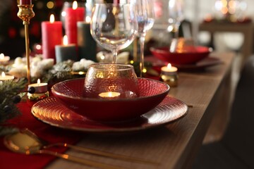 Christmas place setting with festive decor on wooden table in room, closeup
