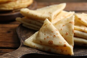 Tasty thin crepes on wooden table, closeup