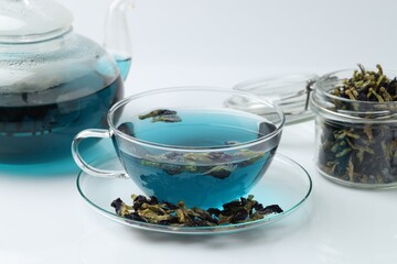 Fresh butterfly pea flower tea and dry petals on white table, closeup