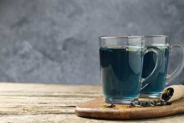 Delicious butterfly pea flower tea on wooden table against gray background, space for text